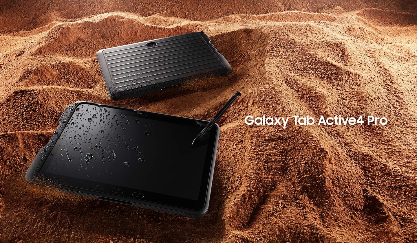Zwei Galaxy Tab Active4 Pro-Geräte, Vorder- und Rückseite, mit S Pen in sandigem Gelände mit Wasser- und Staubspritzern