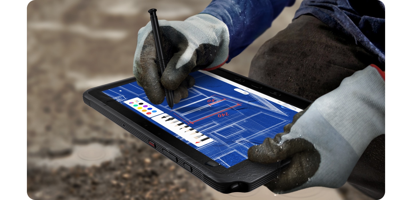 'Arbeiter im Freien mit Handschuhen beim Zeichnen einer Blaupause mit Galaxy Tab Active4 Pro und S Pen