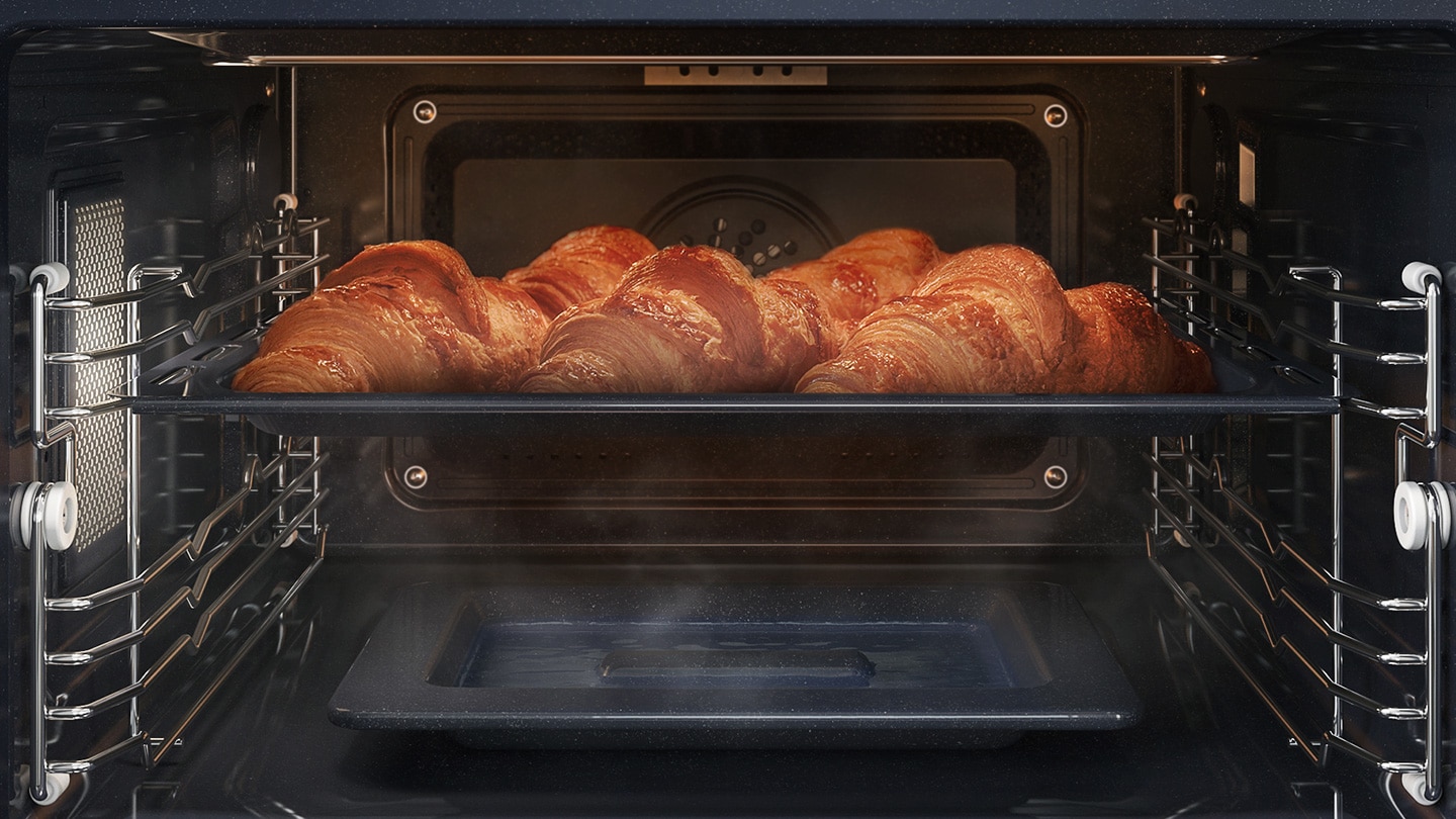 Shows a tray of croissants inside the oven being cooked using the convection system, while being surrounded by steam that is rising from a dedicated tray on the bottom of the oven.