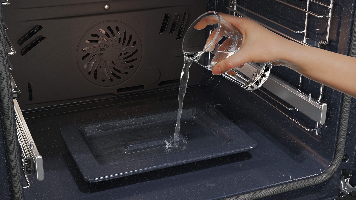 Shows a person pouring water from a glass into a dedicated tray on the bottom of the oven, which is used to create steam.