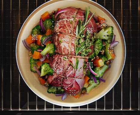 Shows a dish containing a joint of roast meat surrounded by roast vegetables.