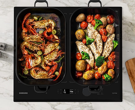 Delicious food in two large rectangular pans is being cooked on the cooktop.