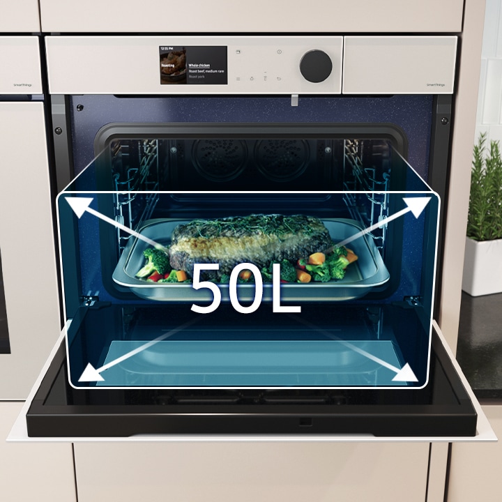 Shows a large tray of food cooking inside the spacious oven with arrows illustrating its 50 liter capacity.