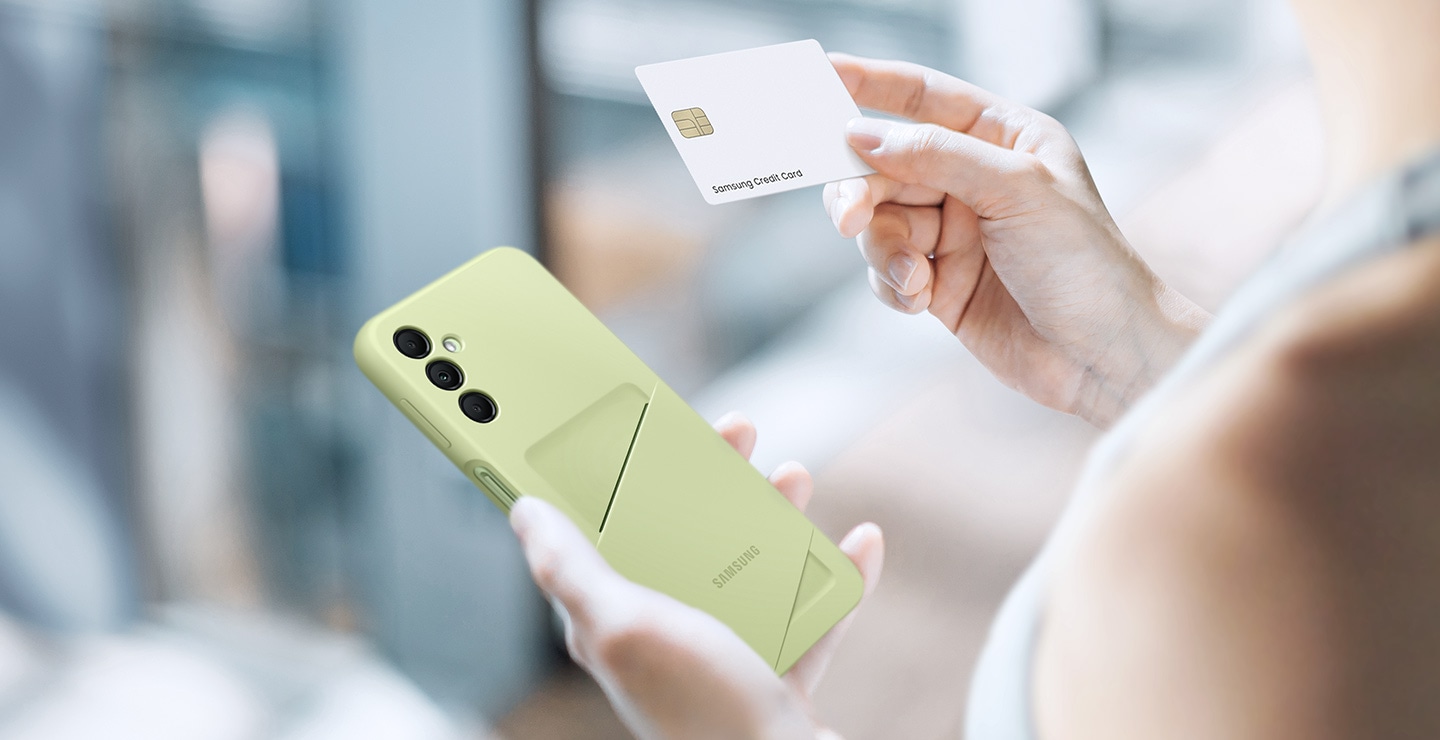 Eine Person hält in der linken Hand ein Galaxy A14 5G mit dem Card Slot Case in der Farbe Lime und in der rechten Hand eine weiße Kreditkarte.