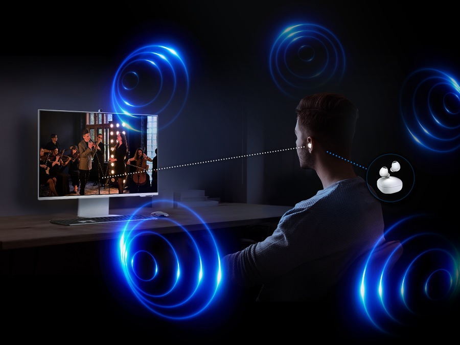 There is a man sitting in front of the monitor. He is listening to the content on the monitor with a Galaxy Buds. Around him, there are some circles which represent spatial sound experience of 360 Audio Mode.