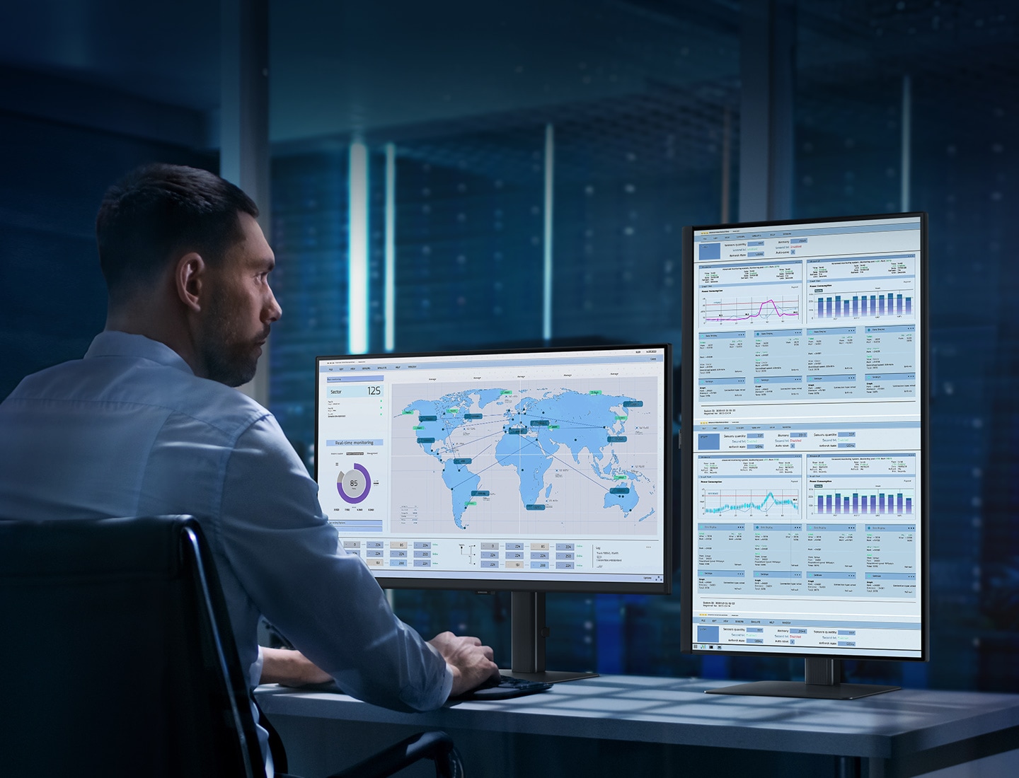 A man sits at a desk in front of a server rack. He is using two monitors. The left monitor is horizontal, showing a world map. The right monitor is vertical, showing numerous graphs and charts. Above the monitor reads "Expand your creative realm."