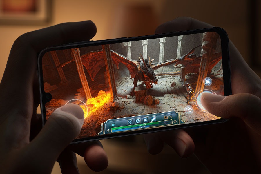 Zwei Hände, die ein Galaxy A16 festhalten und in einem schwach beleuchteten Raum ein grafikintensives Videospiel spielen.