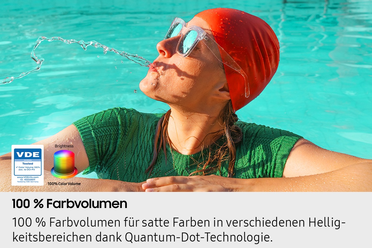 Eine Frau spuckt Wasser im Pool aus. Mit zunehmender Helligkeit werden alle Farben im Bild lebendiger. Das VDE-geprüfte Logo ist zu sehen.