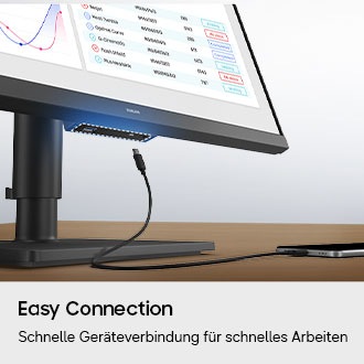 Ein Anschluss an der Unterseite des Monitors ist hervorgehoben, und ein Ladegerät für ein Smartphone wird dargestellt, das versucht, eine Verbindung herzustellen.