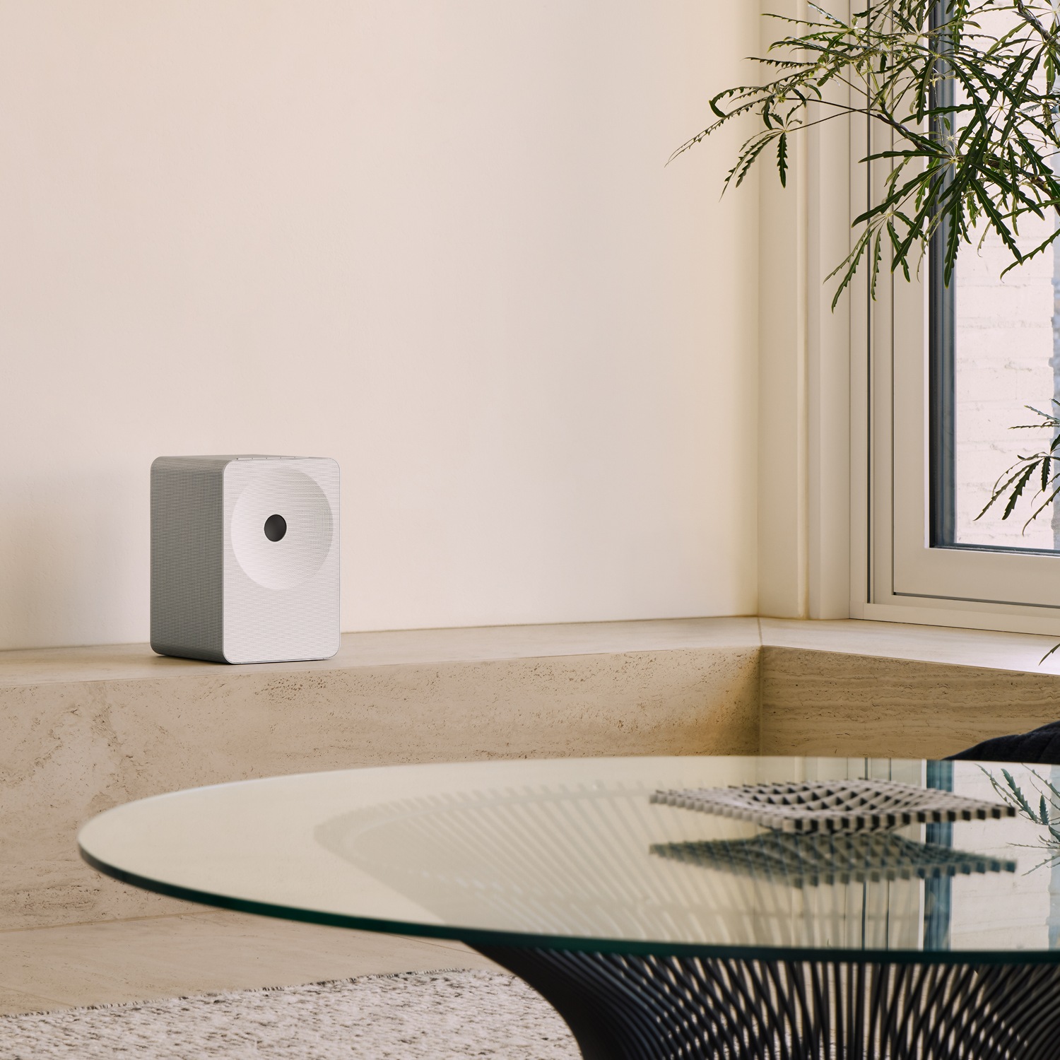 Music Studio 7-højttaler på en beige hylde. Højttaleren står blandt dekoration og en plante og skaber en varm, hyggelig atmosfære i en moderne bolig.