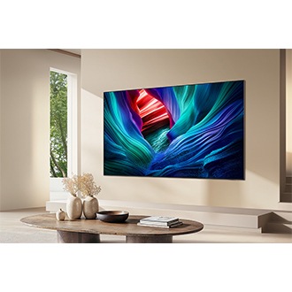 Et stort Samsung Micro RGB-TV, der viser en farverig, abstrakt scene, er monteret på en væg i et lyst rum.