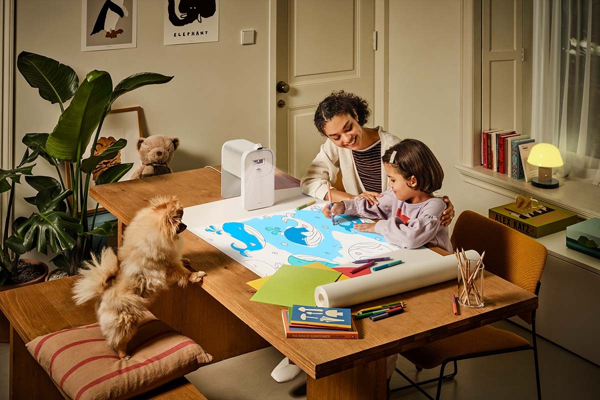 En mor og datter farvelægger et billede, der projiceres på bordet af The Premiere.