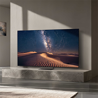 I et moderne hjemmemiljø viser et stort Samsung Micro RGB‑TV et smukt ørkenlandskab med sandklitter.