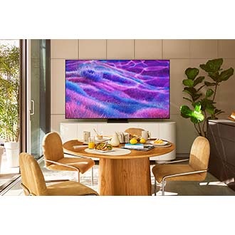 In a sunny kitchen, a TV displays an otherworldly scene of a grassy landscape in vivid shades of blue and purple.