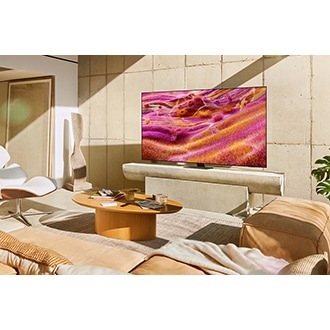 A Neo QLED TV is installed on a stand in a sunny room. The screen displays a colorful abstract landscape.