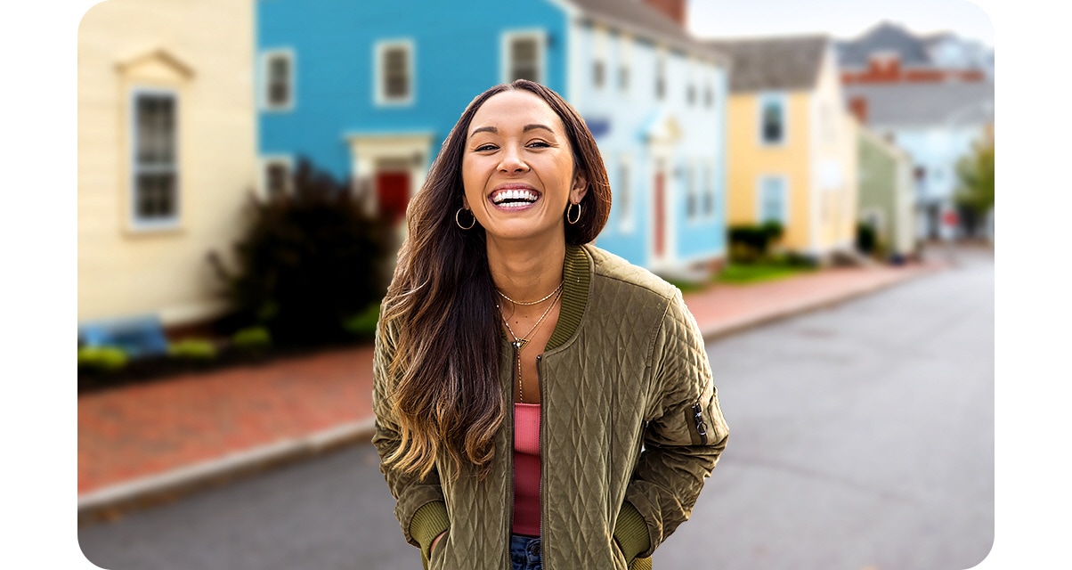 1. A woman is standing in front of colorful houses. However, with the Portrait On icon above activated, the background is blurred and the shot highlights the woman.
