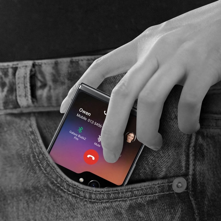 Un Galaxy Z Flip5 con una llamada en curso mostrada en la Flex Window se está sacando de un bolsillo.  La pantalla de llamada muestra la información del contacto además de los controles de Bluetooth, micrófono, teclado y terminar llamada.