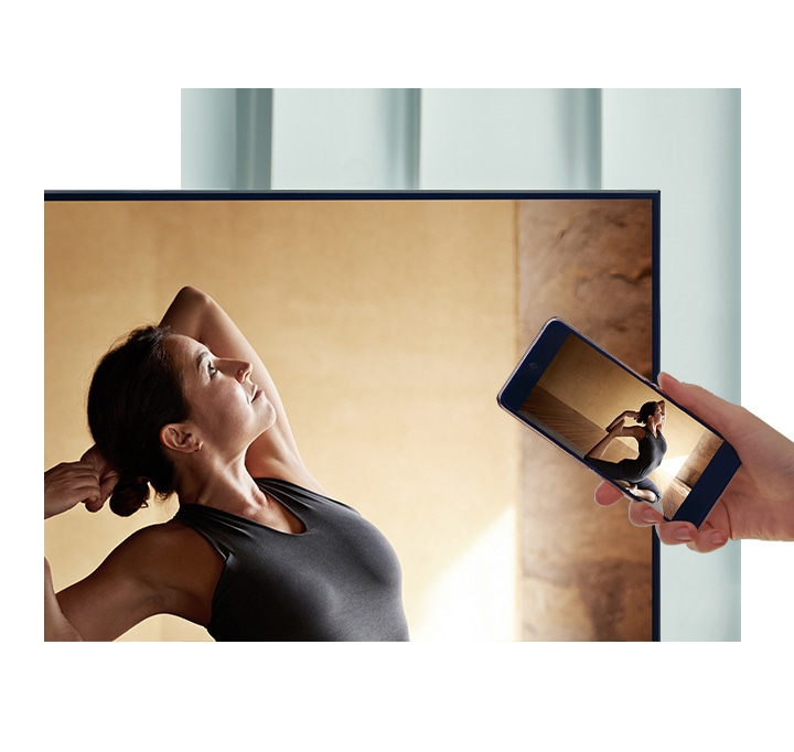 Un usuario conecta su móvil con su televisor QLED para reflejar el contenido de su teléfono a en una pantalla más grande para mayor comodidad.