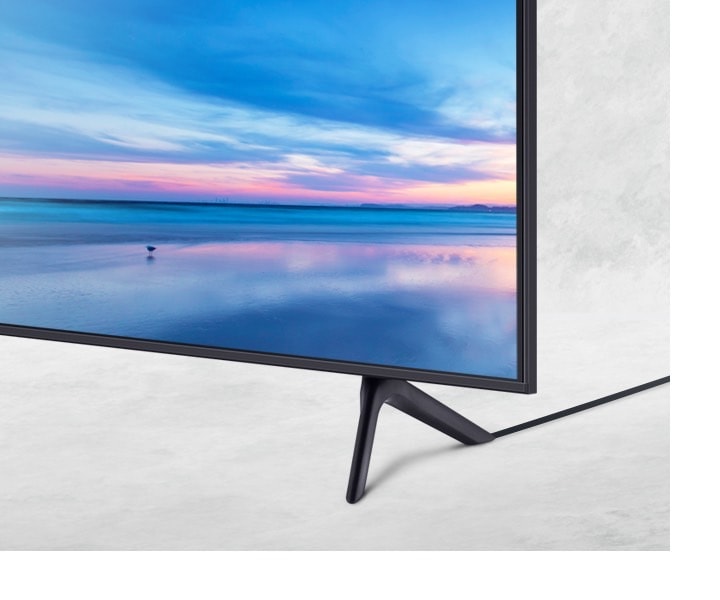 Vista de cerca de uno de los mejores TV Samsung el AU7000 con soporte que genera menos distracción visual gracias a su solución de cable limpio