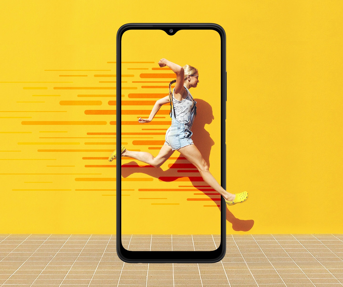 Un Galaxy A22 5G se ve de frente. En la pantalla, una mujer salta hacia adelante contra una pared amarilla, con líneas rojas que demuestran movimiento. Su movimiento se expande más allá de la pantalla del teléfono.