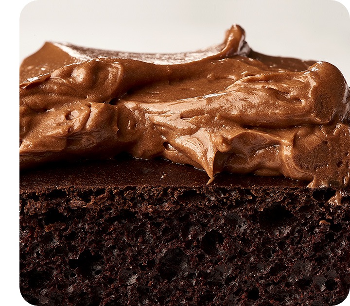 Un primer plano extremo de la sección transversal de un pastel de chocolate, que muestra los detalles de la textura del pastel y el remolino del glaseado.
