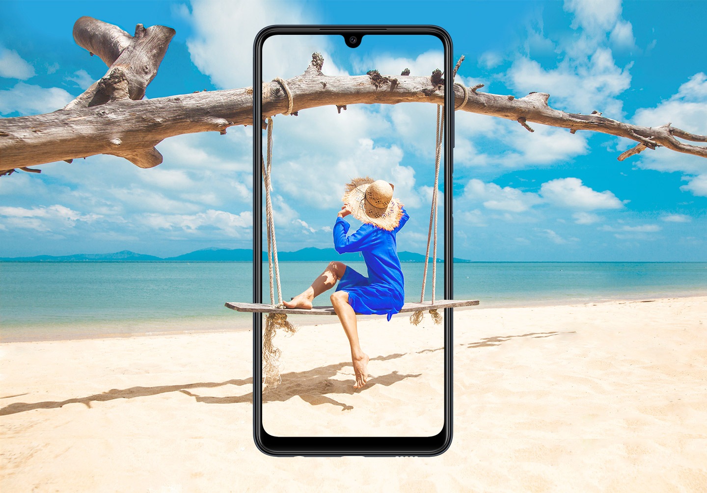 A Galaxy M22 is seen from the front, vertically.  On the screen, a woman sits on a wooden swing hanging from a branch, and beyond the bevel merges with the sandy beach.