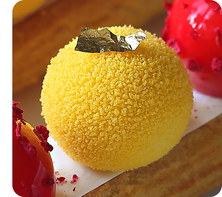 A detailed closeup of a colorful yellow dessert taken with the macro camera with all the texture and garnish details clear.