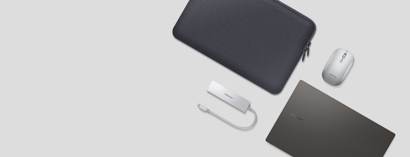 A Galaxy Book3 in the color graphite is shown with its cover closed, displayed alongside a Multiport Adapter, Bluetooth Mouse Slim, and a gray neoprene pouch.
