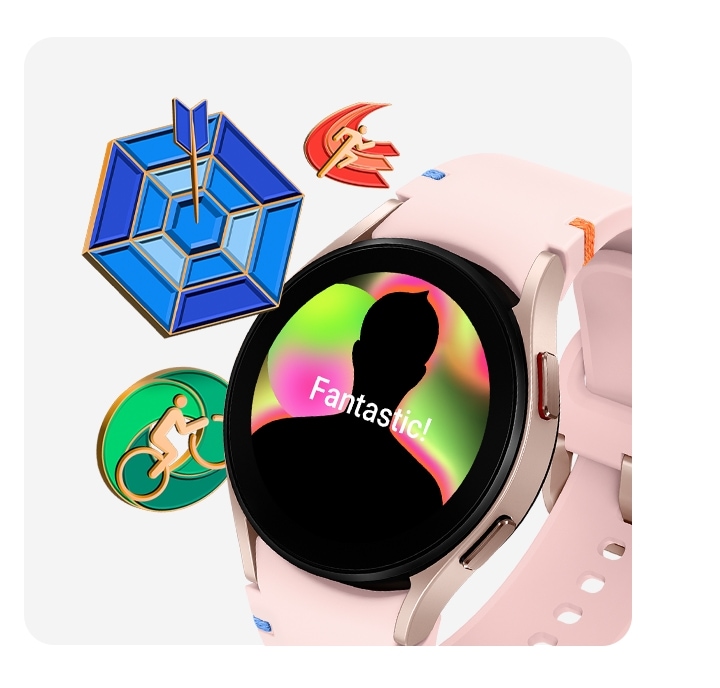 A pink gold Galaxy Watch FE with a pink stitch band is seen from the slanted left front. The watch face displays a reward badge congratulating the user's accomplishment. To the left of the watch, there are three other reward badges: a running badge, an arrow hitting a bulls-eye on a target, and a person on a bicycle.