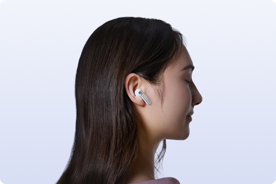 Auriculares Galaxy Buds4 blancos en primer plano, destacando las cuchillas de metal real en diferentes ángulos. La escena cambia y una persona lleva los Galaxy Buds4 en blanco, mirando hacia la derecha.