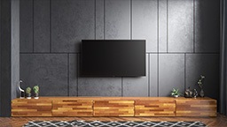 Crystal UHD TV on asennettu harmaalle seinälle puunvärisen TV-kalusteen yläpuolelle. 