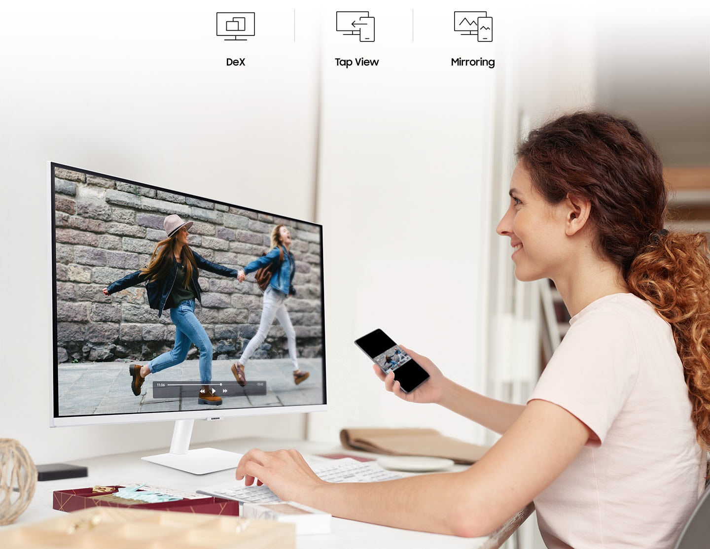 A smiling woman mirrors videos from her phone to her monitor. At the top are the DeX, Tap View, and Mirroring icons.