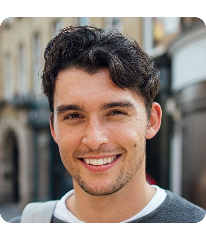 Un homme regarde l'appareil photo, prenant un selfie. L'arrière-plan est subtilement flouté avec l'effet bokeh.