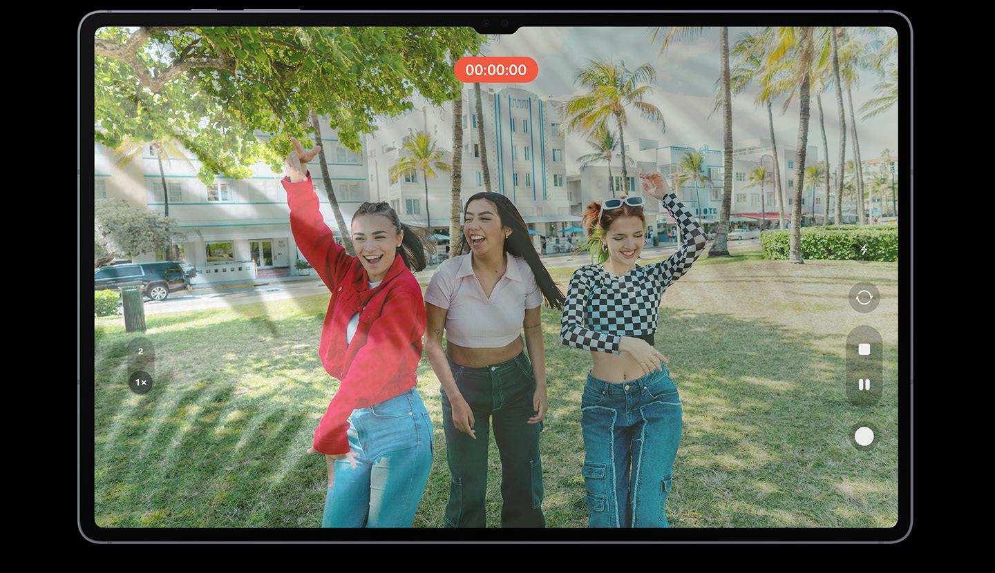 L'écran de la tablette montre un enregistrement vidéo de trois femmes posant joyeusement. Il y a quelques reflets et éblouissements sur l'écran, ce qui rend l'image affichée sur l'écran peu claire.