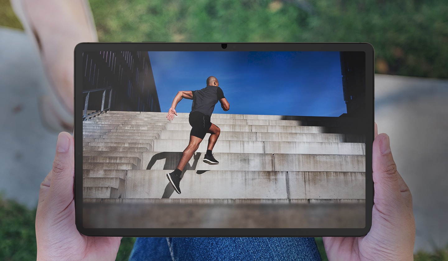 Μπροστινή άποψη ενός Galaxy Tab S9+, το οποίο το κρατάει ένα άτομο σε εξωτερικό χώρο, με θάμπωμα και αντανάκλαση να είναι ορατά στην οθόνη.