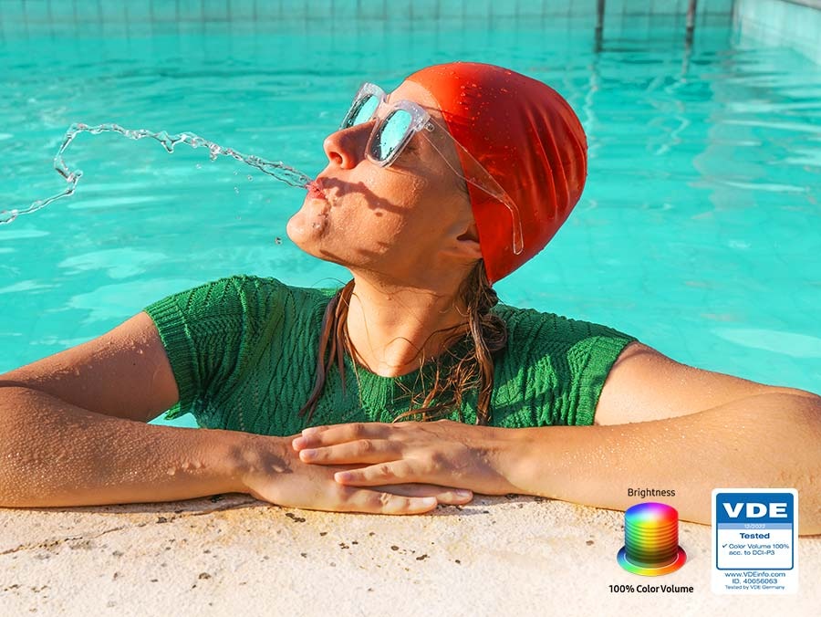 Bir kadın havuza su tükürüyor. Parlaklık seviyesi arttıkça görüntüdeki tüm renkler canlı hale gelir. VDE tarafından test edilmiş logo sergileniyor.