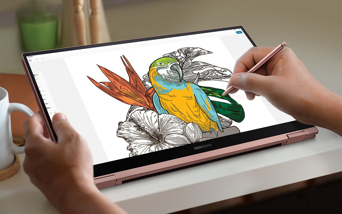A woman uses S Pen to color in a drawing of tropical objects like flowers and a bird on PENUP app.