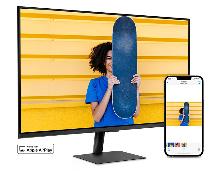 A smartphone and monitor sit side-by-side. The smartphone shows a woman posing with a skateboard. The same woman with skateboard is shown on the monitor. The smartphone's gallery app swipes through different photos which are also shown on the monitor screen.