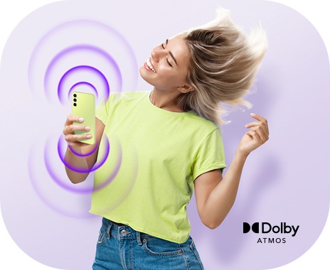 一位手持霧冰青 Galaxy A34 5G 的女士正在隨著她裝置中的音樂跳舞，顯示裝置頂部和底部開始的同心圓。右側顯示了杜比全景聲 (Dolby Atmos) 徽標。