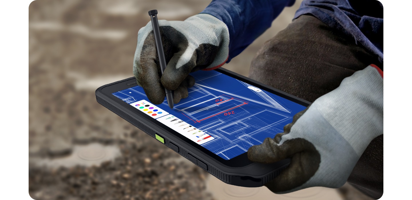 圖中一名工人戴著重型手套，使用 S Pen 在 Galaxy Tab Active5 5G 裝置上繪制建築設計。背景顯示的是崎嶇的地形。
