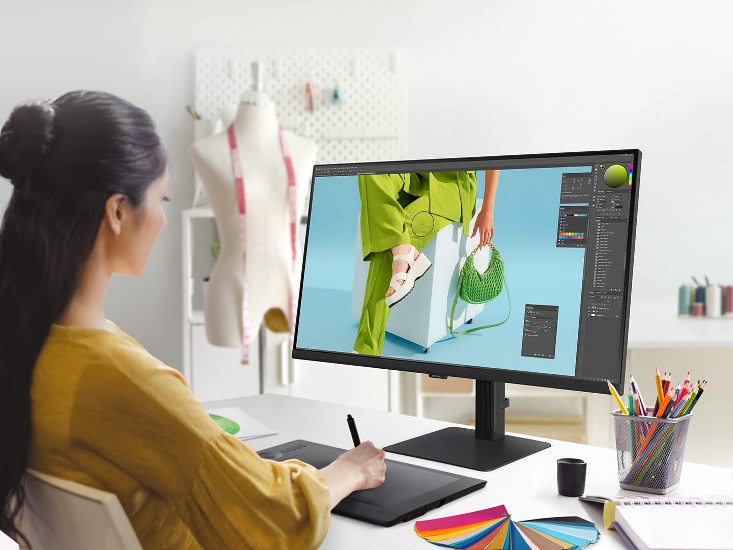 A woman sits at a desk with a photo editing software on her screen. Above the monitor reads "Expand your creative realm."