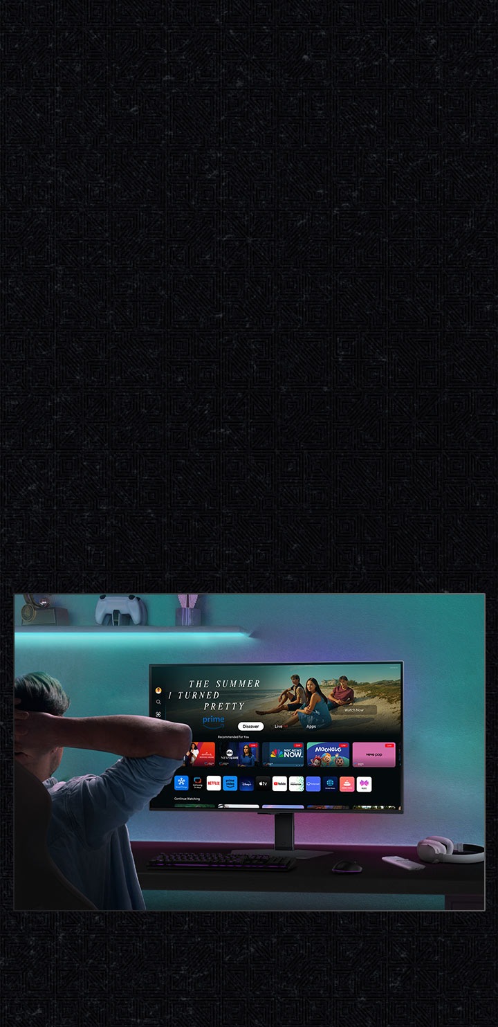A gamer leans back in their chair in front of the monitor, reviewing Smart Hub home display with video app options such as Netflix and Amazon Prime.