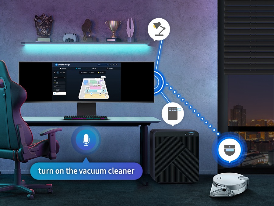 There is a monitor in a room with a vacuum cleaner, air purifier, and blind. All the devices are connected with the monitor with SmartThings, and the vacuum cleaner is activated by commanding at the SmartThings hub on the monitor in a voice saying 'turn on the vacuum cleaner'.