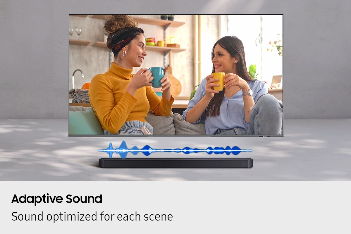 A TV displays a scene of two women chatting. Below it, a soundbar plays the sound at a volume suitable for dialog.