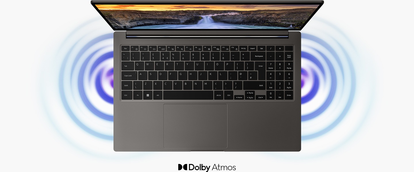 A top view of a graphite Galaxy Book3, open and facing forward with a natural landscape wallpaper onscreen and sound waves coming out of the two speakers. Dolby Atmos logo is shown.