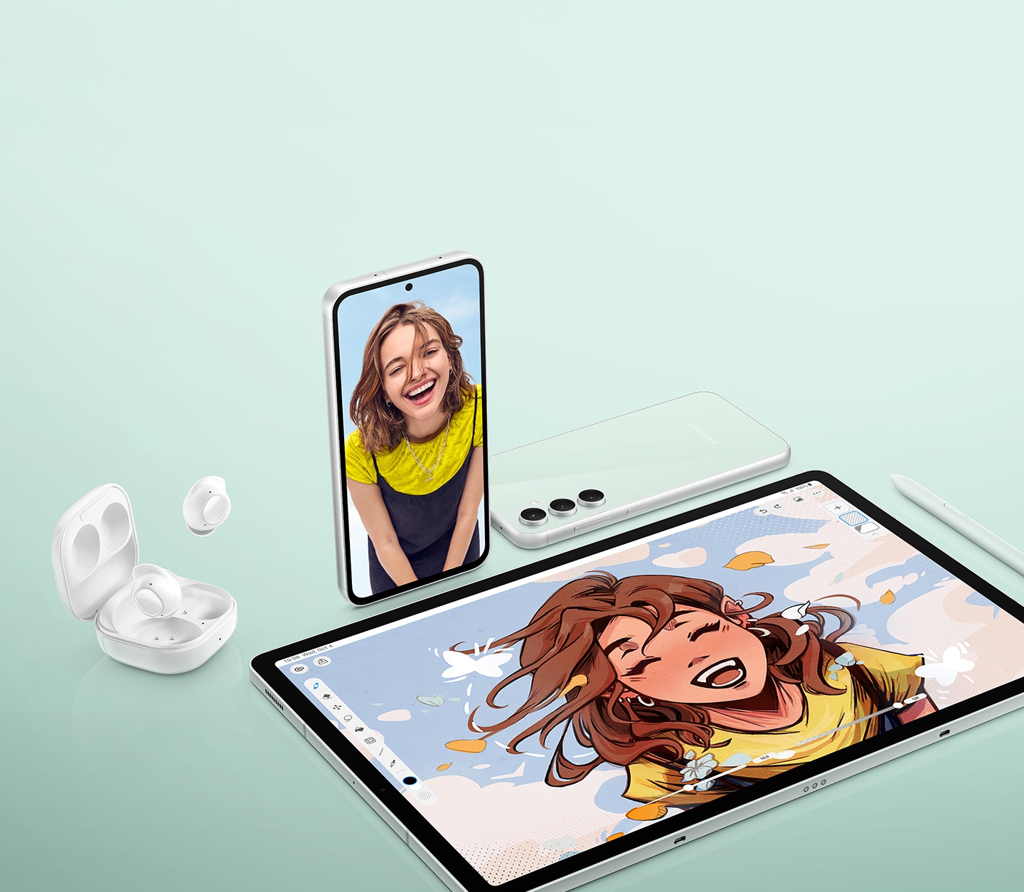 An open case of Galaxy Buds FE is seen with one earbud inside and one earbud outside. A Galaxy S23 FE device stands upright with a smiling woman on its screen. Another Galaxy S23 FE device lies face down showing its rear. A Galaxy Tab S9 FE Plus tablet shows a digital drawing of the smiling woman, with an S Pen placed nearby.