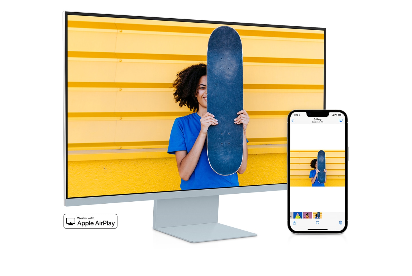 Pametni telefon i monitor sjede jedan pored drugog. Pametni telefon prikazuje ženu koja pozira sa skateboardom. Na monitoru je prikazana ista žena sa skateboardom. Aplikacija galerija pametnog telefona prevlači se kroz različite fotografije koje se također prikazuju na zaslonu monitora.