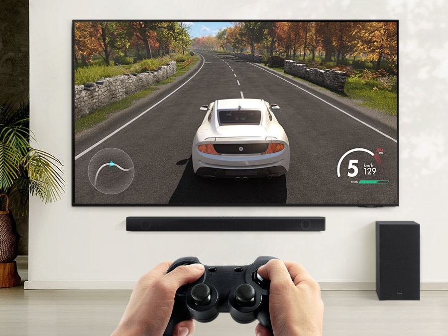 Korisnik uživa u načinu igre soundbara dok igra trkaću igru ​​na svom TV-u spojenom na soundbar i subwoofer.