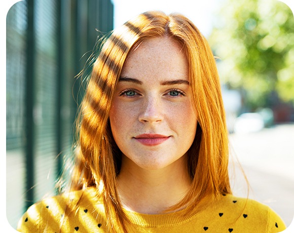 Vani je žena i smiješi se u kameru. Pozadina je zamućena pa se ona ističe.