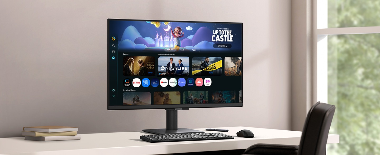 Monitor na stolu prikazuje stranicu Smart TV aplikacija s raznim sadržajem i aplikacijama poredanim po redu.